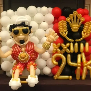 Gold and red balloon display with a fun character sculpture and decorative backdrop, perfect for themed celebrations and stage decor.