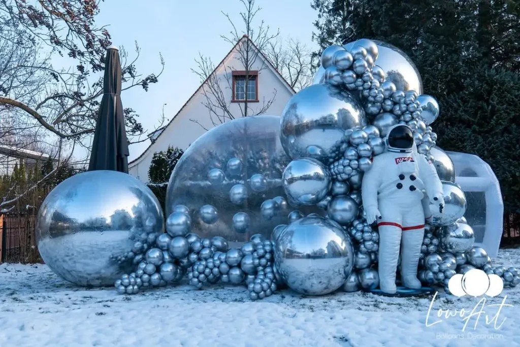 Shiny silver balloon installation outdoors with astronaut figure for themed event